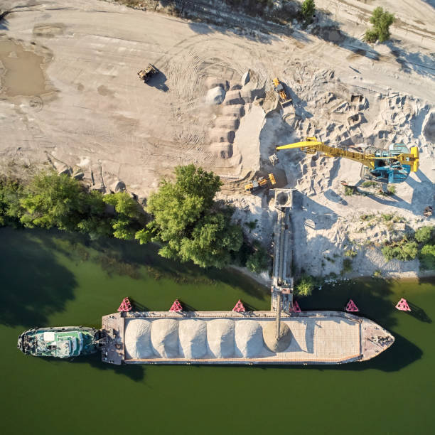 Une grue charge du sable et du gravier sur une barge Géomouv pour le transport fluvial. Drone aérien.